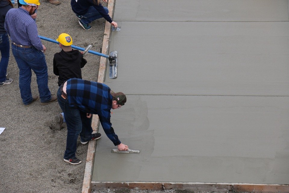 Concrete flatwork being leveled inside prepared forms
